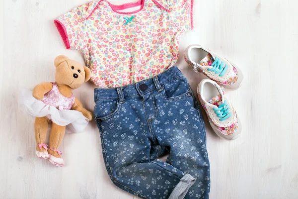 Set of children's clothing and shoes on a wooden background — Stock Photo, Image