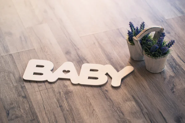 The word baby in wooden letters on the floor with a pot of lavender — Stock Photo, Image