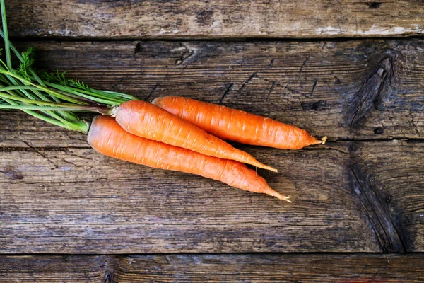Куча свежей моркови с зелеными листьями на деревянном фоне. Овощи. Еда — стоковое фото