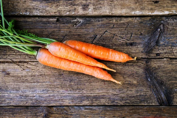 Manojo de zanahorias frescas con hojas verdes sobre fondo de madera. Hortalizas. Comida — Foto de Stock