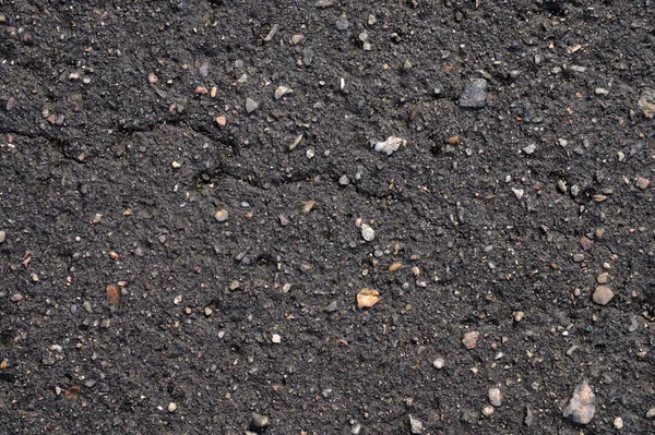 Abstrakt bakgrund av svart våt asfalt med inneslutningar av småsten — Stockfoto