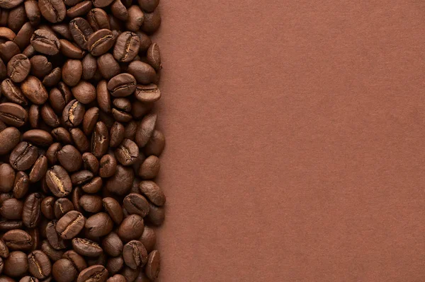 Roasted coffee beans on brown background with copy space. Close up top view. — Stock Photo, Image