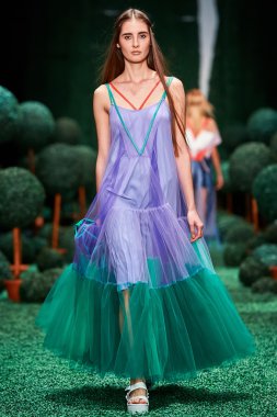 Bir model Alena Akhmadullina podyum üzerinde yürüyor