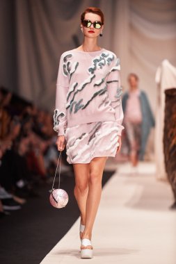 Bir model Alena Akhmadullina podyum üzerinde yürüyor