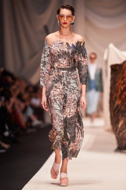 Bir model Alena Akhmadullina podyum üzerinde yürüyor