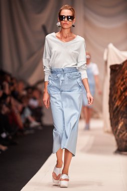 Bir model Alena Akhmadullina podyum üzerinde yürüyor