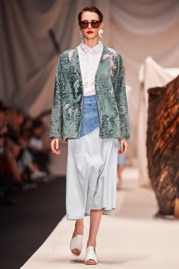 Bir model Alena Akhmadullina podyum üzerinde yürüyor