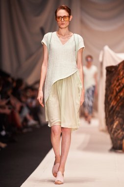 Bir model Alena Akhmadullina podyum üzerinde yürüyor