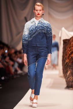 Bir model Alena Akhmadullina podyum üzerinde yürüyor