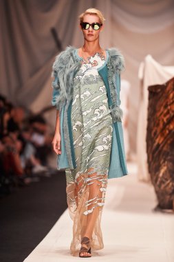 Bir model Alena Akhmadullina podyum üzerinde yürüyor