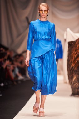 Bir model Alena Akhmadullina podyum üzerinde yürüyor