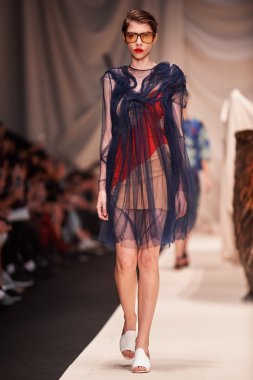 Bir model Alena Akhmadullina podyum üzerinde yürüyor