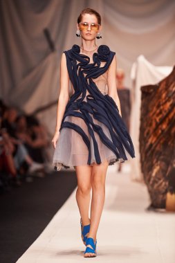 Bir model Alena Akhmadullina podyum üzerinde yürüyor