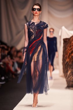 Bir model Alena Akhmadullina podyum üzerinde yürüyor