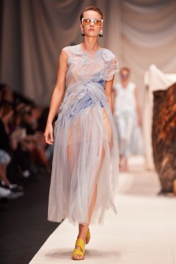 Bir model Alena Akhmadullina podyum üzerinde yürüyor