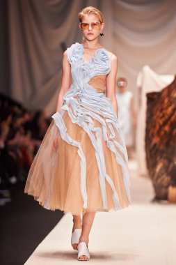 Bir model Alena Akhmadullina podyum üzerinde yürüyor