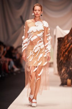 Bir model Alena Akhmadullina podyum üzerinde yürüyor