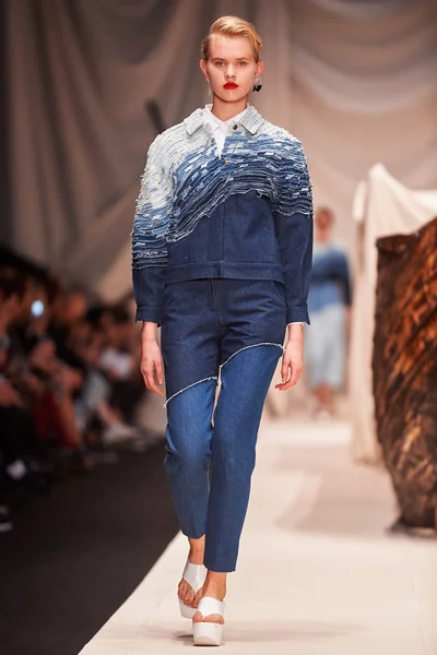 Bir model Alena Akhmadullina podyum üzerinde yürüyor