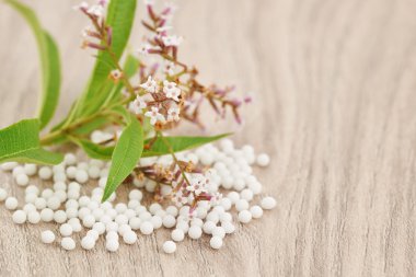 Ahşap bir masa üzerinde dağınık homeopatik granül