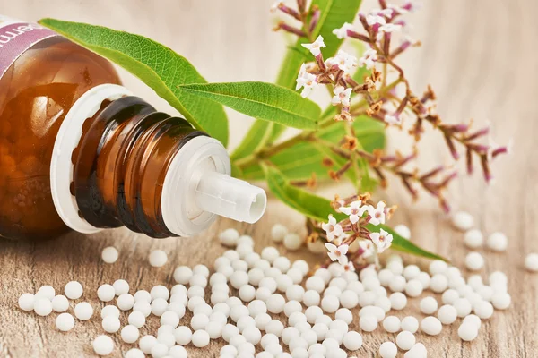 Homeopathische korrels verspreid over een houten tafel — Stockfoto