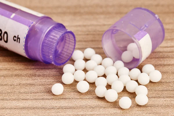 Homeopathische bolletjes en paarse containers — Stockfoto