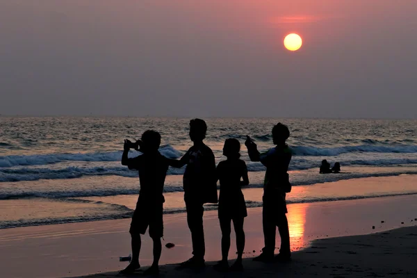ビーチで夕日の写真を撮る人々 のシルエット — ストック写真