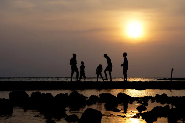 Grupo de pessoas ao pôr do sol na praia — Fotografia de Stock