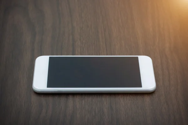 Teléfono inteligente con pantalla en blanco tumbado en la mesa de madera — Foto de Stock