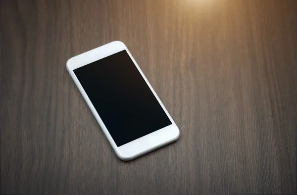 Teléfono inteligente con pantalla en blanco tumbado en la mesa de madera — Foto de Stock