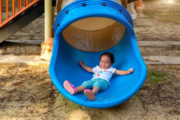 An Asian girl is enjoy on a playground equipment in a school.