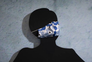 Siyah bir mankene COVID 19 koruyucu maske takılır..