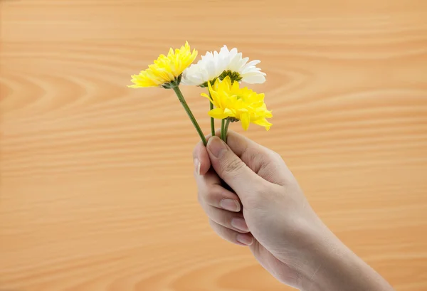 木製の背景に花の束を持つ女性の手 — ストック写真