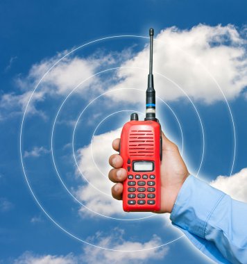 Kırmızı taşınabilir radyo alıcı-verici mavi gökyüzü üzerinde elinde