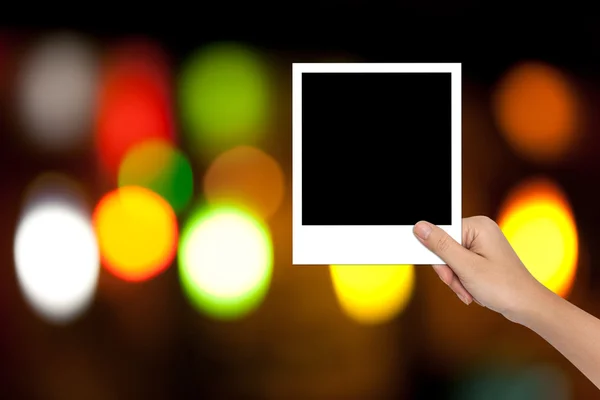 Hand van vrouwelijke Holding een lege fotolijst op kleurrijke bokeh bac — Stockfoto