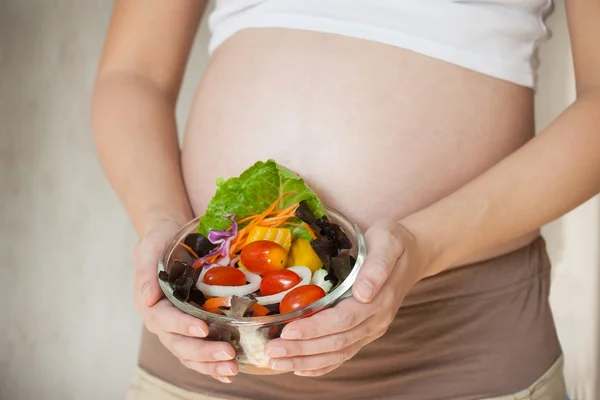 孕妇的肚子和蔬菜沙拉 — 图库照片