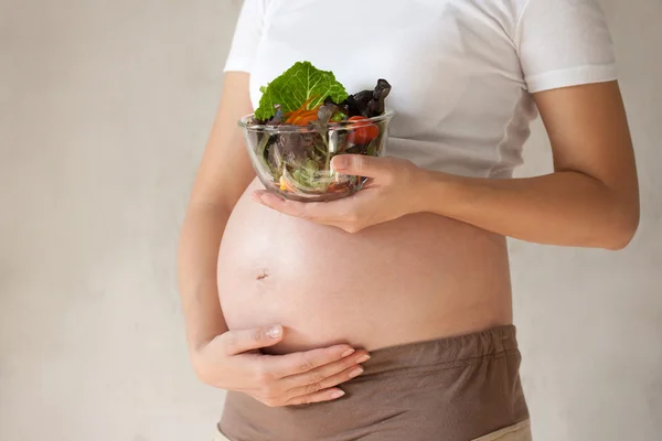 Schwangerschaftsbauch und Gemüsesalat — Stockfoto