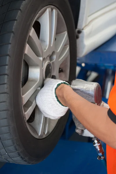 Mecánico del coche que atornilla o desenrosca la rueda del coche del automobi levantado —  Fotos de Stock