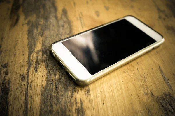Teléfono inteligente con pantalla en blanco acostado en la mesa — Foto de Stock