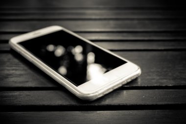 Masanın üzerinde yatan boş ekranlı akıllı telefon