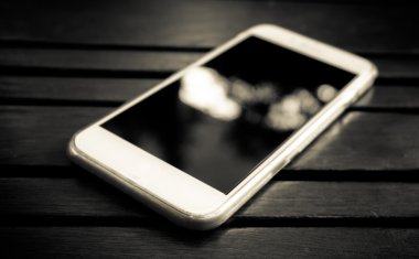 Masanın üzerinde yatan boş ekranlı akıllı telefon