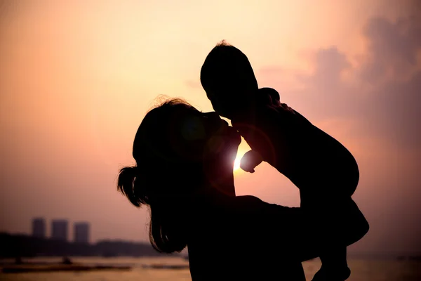 Silhouette einer Mutter spielt mit ihrem Kleinkind gegen den Sonnenuntergang. — Stockfoto