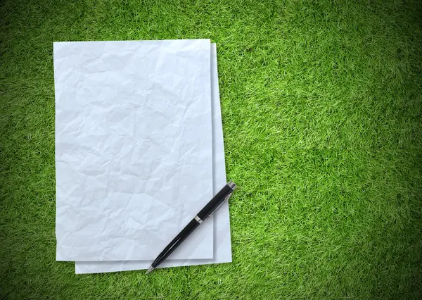 Белый лист бумаги на зеленом фоне травы — стоковое фото