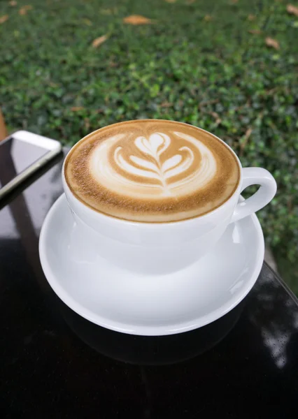Šálky kávy na černém stole latte umění — Stock fotografie