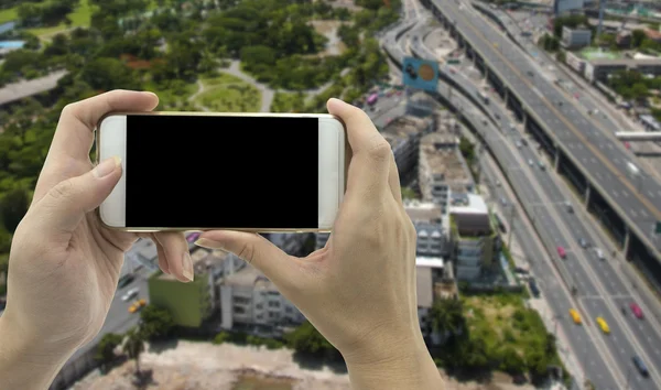 Female Hand holding smart phone over traffic road background