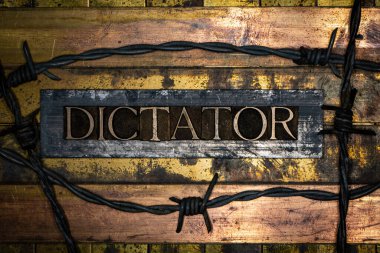 Dictator text on grungy textured authentic copper and gold background lined with bronze bars and rusty barbed wire