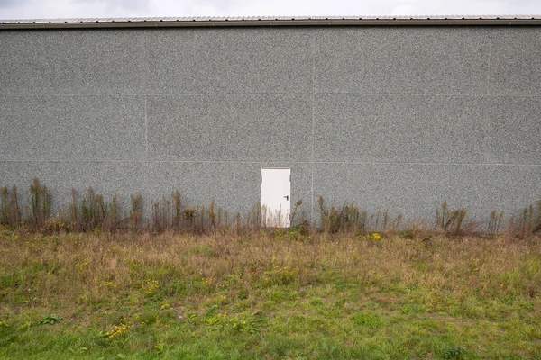 小さな白いドアが一つある大きな灰色の建物 — ストック写真