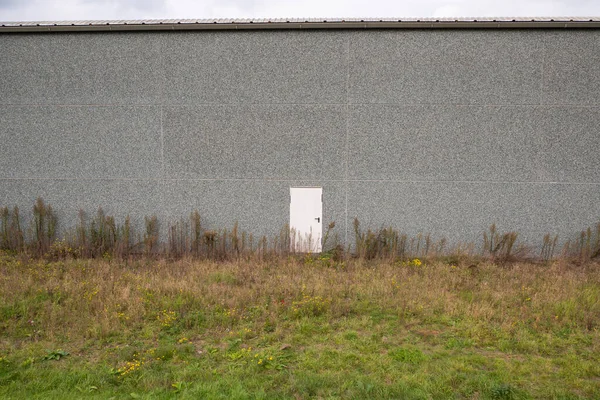 Groot Grijs Gebouw Met Een Enkele Kleine Witte Deur — Stockfoto