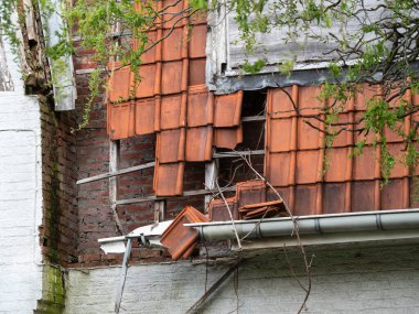 Terk edilmiş bir gecekondu evinden turuncu kiremitler düşüyor.