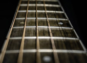 Detailní záběr na kytaře fretboard pomocí mělké hloubky pilníku a černého pozadí.