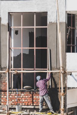 16 Ocak 2026 Dehradun Hindistan. Hindistan 'da modern tasarımlı konut inşaatı sırasında pencere pervazlarını sıvayan inşaat işçisi.